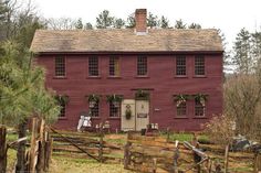 an old red house with wreaths on the windows