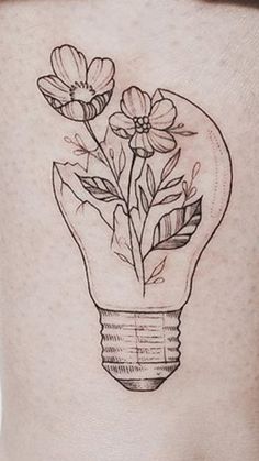 a woman's thigh with flowers in a light bulb tattoo