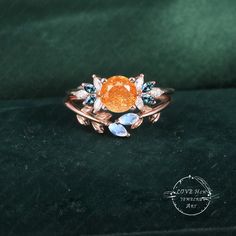 an orange and blue ring sitting on top of a green velvet covered surface with the words love each other