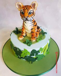 there is a cake decorated with a tiger on the top and green leaves around it