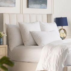 a bed with white sheets and pillows in a bedroom