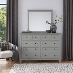 a room with a dresser, chair and mirror on it's side in front of a window