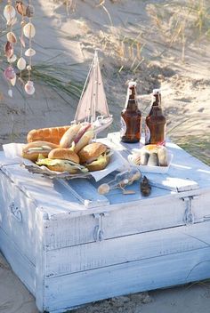 an old trunk is sitting on the beach with food and beer in front of it