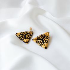 pair of yellow and black beaded triangle earrings on white silk background, closeup