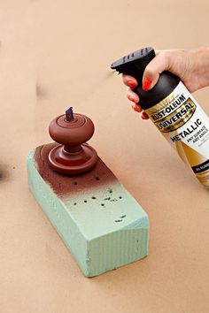 a person is spray painting a piece of wood