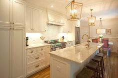 a large kitchen with white cabinets and marble counter tops, along with an island in the middle