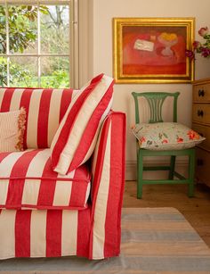 a red and white striped couch sitting in a living room next to a green chair