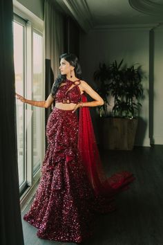 a woman standing in front of a window wearing a red sequined dress and matching shawl