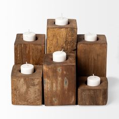 several wooden blocks with candles in them on a white surface, one is stacked up and the other has three smaller ones