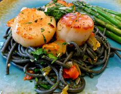 scallops and noodles on a blue plate with asparagus