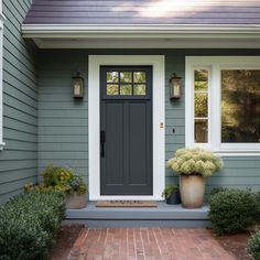 a gray house with white trim and two large planters