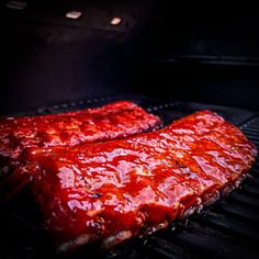 two ribs covered in bbq sauce cooking on the grill