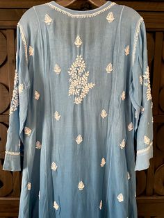 This Blue Ombre Muslin Silk Handcrafted Lucknowi Chikankari A Line Kurta Long Dress is a stunning piece of art. The beautiful blue shade dress is perfect for any special occasion. The luxurious fabric and intricate Lucknowi Chikankari embroidery make it a timeless piece that will never go out of style. Length 48" inches Long sleeves 18" inches Round neck A line Muslin silk Chikankari work Hand embroidered Dry Clean Fit: True to sizeInside Margin: NoTouch and Feel: Soft and ComfortableDispatched Blue Bohemian Kurta With Dupatta, Blue Chanderi Dresses With Cutdana, Indigo Traditional Wear With Chikankari Embroidery And Long Sleeves, Indigo Kurta With Chikankari Embroidery For Festivals, Elegant Cutdana Kurta For Summer, Transitional Blue Salwar Kameez With Floral Embroidery, Blue Traditional Drape Kurta For Summer, Indigo Salwar Kameez With Chikankari Embroidery, Blue Mulmul Kurta With Resham Embroidery