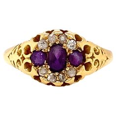 This wonderful cluster ring is a true testament to antique charm and intricate craftsmanship. The rings' focal point is an arrangement of 3 horizontally set rich purple amethysts, with the central amethyst slightly larger than the two flanking stones, all expertly set in open back claw settings with an approximate combined weight of 0.45 ct. Surrounding the central stones are 8 delicate old cut diamonds, weighing approximately 0.12ct combined, meticulously set in a floral pattern, above and below the amethysts, creating a halo effect that enhances the overall elegance of the piece. The 18 carat yellow gold band itself is a true piece of art designed with intricate scroll open work detailing tapering gently towards the shoulders, showcasing exceptional artistry and attention to detail. Fina Pearl Cluster Ring, Ruby Diamond Rings, Cluster Engagement Ring, Rich Purple, Pearl Cluster, Bespoke Jewellery, Diamond Cluster Ring, Vintage Diamond, Antique Rings