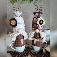 two coffee cups decorated with angel figurines on top of coffee beans and flowers