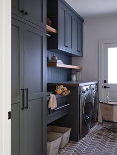 a washer and dryer in a laundry room with gray cabinets on either side