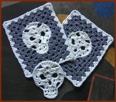 two crocheted squares with white and blue designs on them, sitting on a table