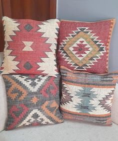 three colorful pillows sitting on top of a white couch