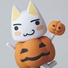 a white cat sitting on top of a jack - o'- lantern figurine