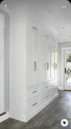 an empty kitchen with white cabinets and wood floors