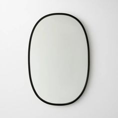 an oval mirror hanging on the wall with black trim around it's edges and bottom edge