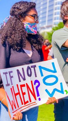 two people holding signs that say if not when?