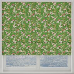 a green floral roman blind with pink and white flowers on the top, in front of a window