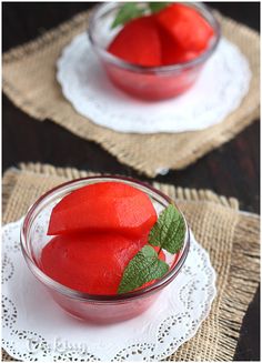 two small bowls filled with red fruit on top of a doily covered place mat