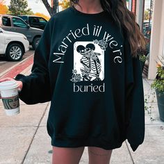 a woman is standing on the sidewalk holding a coffee cup and wearing a black sweatshirt