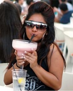 a woman in sunglasses drinking from a drink cup with a straw sticking out of her mouth