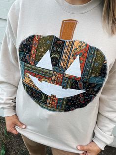 a woman wearing a sweatshirt with an image of a pumpkin painted on it's chest