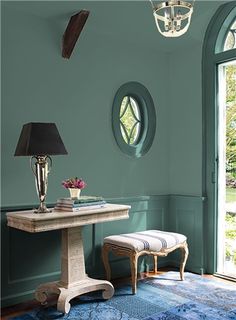 a room with green walls and blue rugs on the floor next to a table