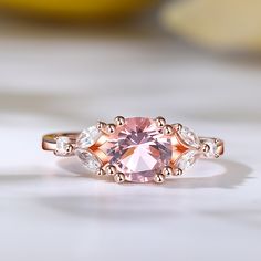 Indulge in the ethereal beauty of the morganite ring, a stunning masterpiece that captures hearts and captivates souls. Crafted with a captivating round-cut morganite as its centerpiece, this ring exudes timeless beauty. The delicate blush hue of the morganite is complemented by the dazzling brilliance of the marquise-cut white stones that gracefully adorn its sides. Embrace the allure of this enchanting piece, where the soft pink hues of the morganite symbolize love and compassion, while the sp Elegant Morganite Diamond Ring With Gemstone, Elegant Morganite Ring With Center Stone, Elegant Morganite Diamond Ring With Round Cut, Elegant Pink Cluster Ring With Brilliant Cut, Elegant Topaz Ring With Morganite In Prong Setting, Exquisite Morganite Diamond Ring For Anniversary, Exquisite Morganite Rings, Elegant Pink Gold Morganite Rings, Exquisite Morganite Rose Gold Rings