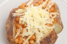 a white plate topped with a baked potato covered in grated cheese and garbanzo beans