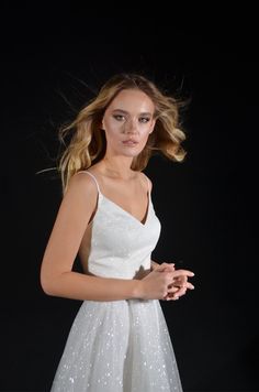 a woman in a white dress posing for the camera with her hair blowing in the wind