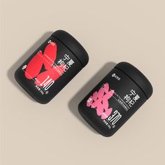 two black containers with pink and red designs on the lids sitting side by side against a beige background