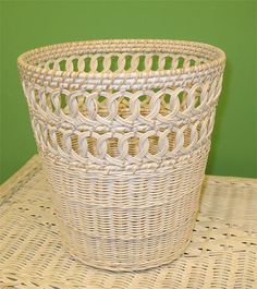 a white wicker basket sitting on top of a table next to a green wall