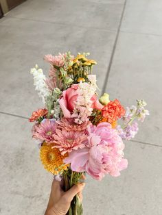 a person holding a bouquet of flowers on the sidewalk