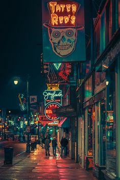 people are walking down the street in front of neon signs and buildings at night time