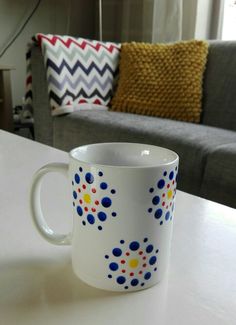 a coffee cup sitting on top of a white table next to a couch and pillows