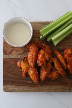 chicken wings and celery on a cutting board next to a bowl of ranch dressing