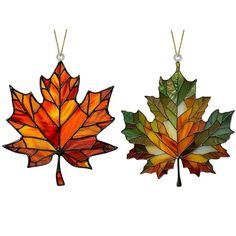 two stained glass maple leaf ornaments hanging from chains on a white background, each with a different color and shape