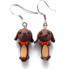 a pair of earrings with a dog wearing a bow tie on it's ear