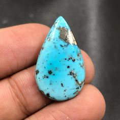 a hand holding a turquoise stone in it's left side and the tip of its end