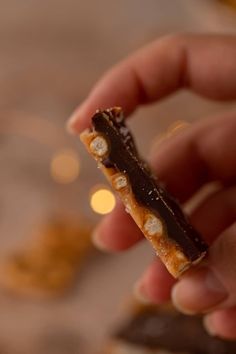 a hand holding a piece of chocolate and caramel candy bar with white dots on it