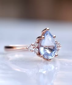 an engagement ring with a pear shaped blue topazte surrounded by small white diamonds