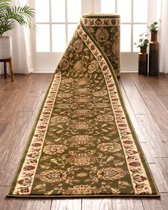 a large green rug is on the floor in front of a window with potted plants