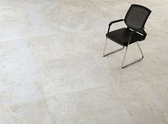 a black office chair sitting on top of a white tile floor next to a window