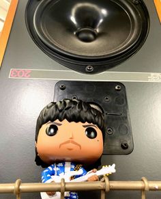 a close up of a figurine on a shelf with speakers in the background