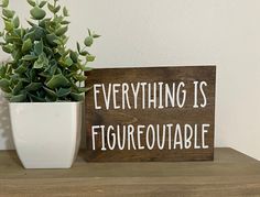 a potted plant sitting next to a wooden sign that says everything is figurequatable